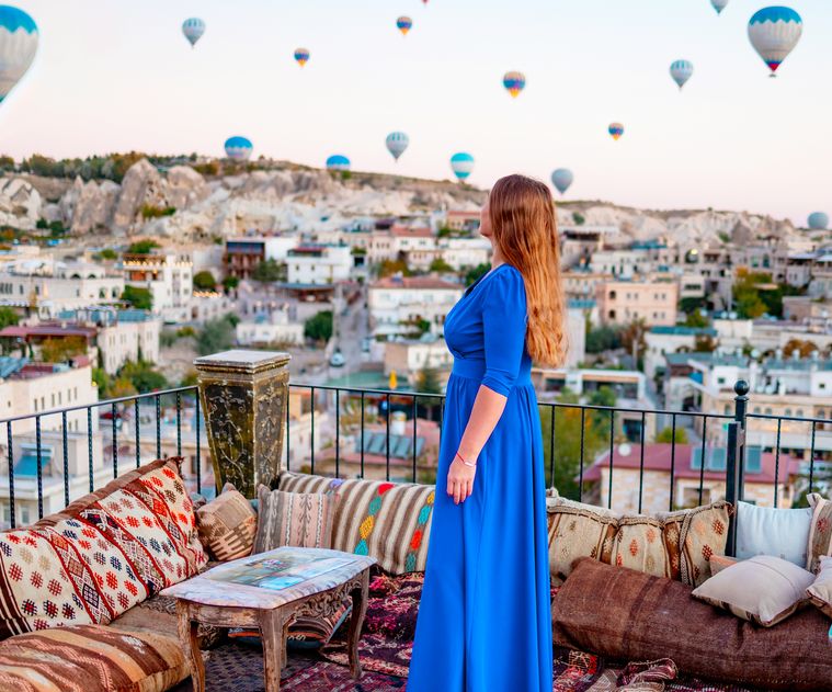 Traveller on a Cappadocia terrace watching hot-air balloons at sunrise — Kackar Tour DMC